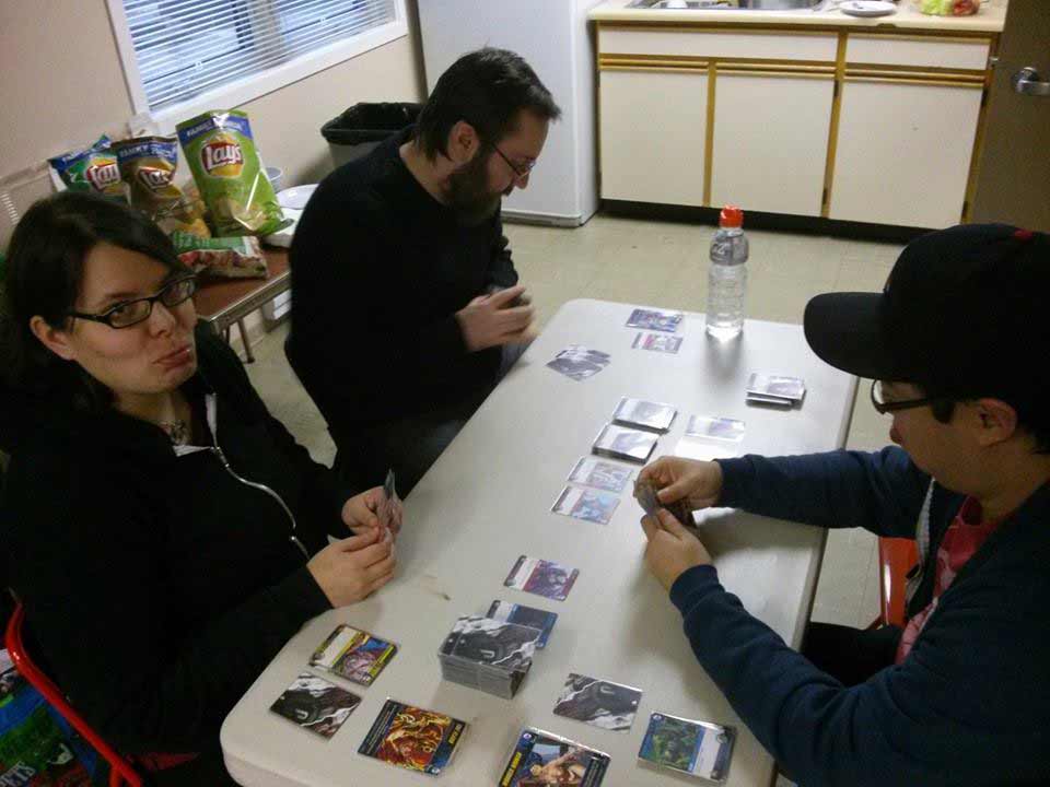 dudes and dudette playing DC Deckbuilding game